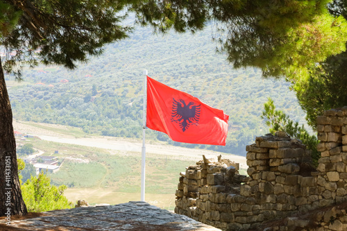 Obraz na plátně A flapping and blowing bright red Flag of Albania on a hill-top castle demonstrating power and strength of a country