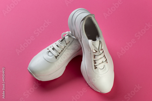 Women's stylish sneakers on a pink background. Lifestyle sneaker sport shoe. Space for text.