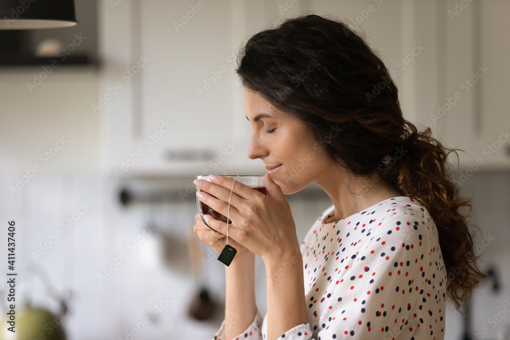 Happy millennial Caucasian woman hold mug drink enjoy hot black tea in the morning at home. Calm young female have warm beverage from cup, relax rest on weekend in cozy home. Hygge concept. Happy millennial Caucasian woman hold mug drink enjoy hot black tea in the morning at home. Calm young female have warm beverage from cup, relax rest on weekend in cozy home. Hygge concept.