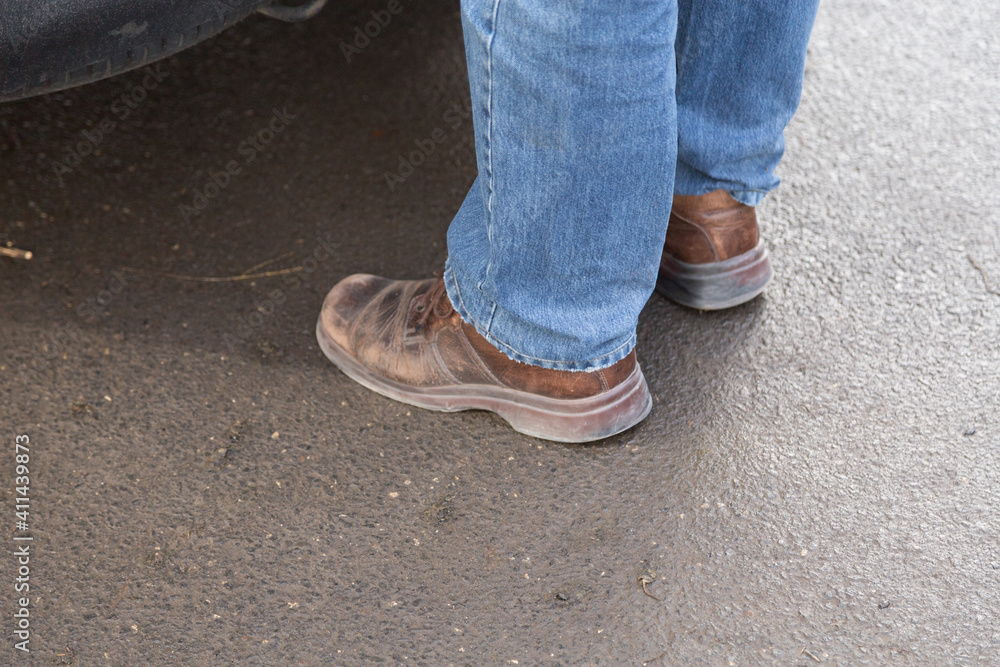 Man's legs in blue denim jeans and brown boots. Man's legs in blue denim jeans and brown boots.
