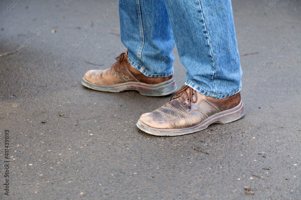 Man's legs in blue denim jeans and brown boots. Man's legs in blue denim jeans and brown boots.