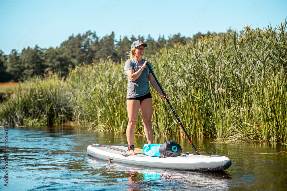Woman rowing with SUP stand up paddle board in river. Front view