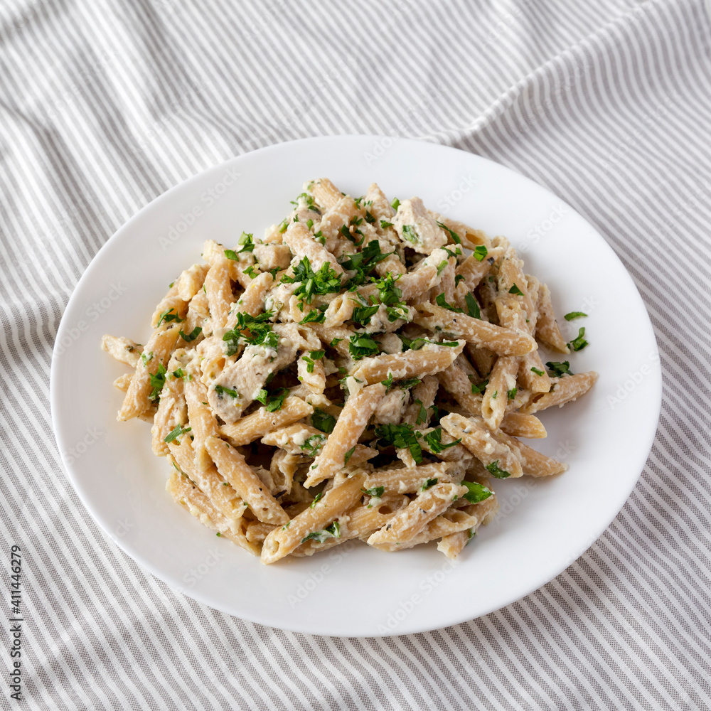 Homemade Chicken Alfredo Penne with Parsley on a white plate, side view. Homemade Chicken Alfredo Penne with Parsley on a white plate, side view.
