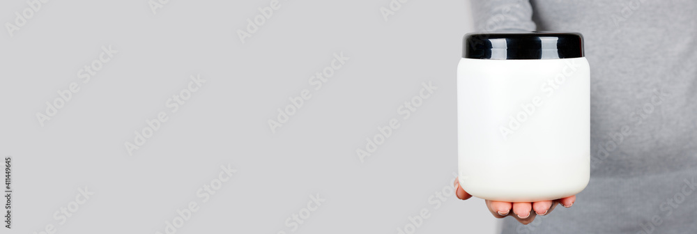 Hand with white cosmetic bottle isolated on grey background. Hand with white cosmetic bottle isolated on grey background.