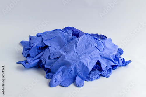 Big pile of thin blue medical latex gloves on light background. Disposable rubber medical gloves. Protective subjects. Remedies. Close-up. Selective focus. Copy space.