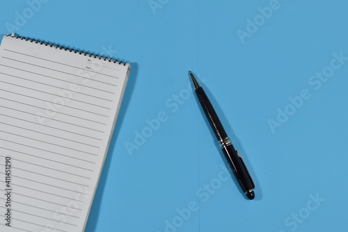 An Elegant Black Ball Pen On A Notebook Isolated WIth Pastel Bluee Background photo