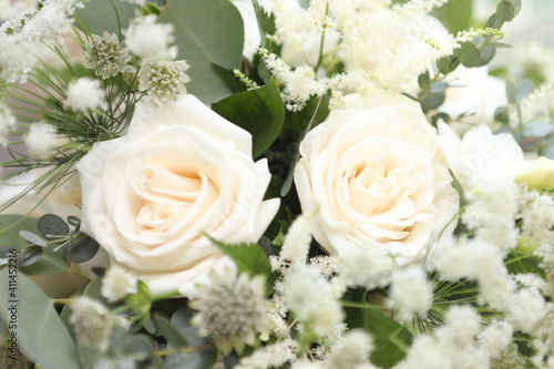 White roses with green leaves and other white flowers