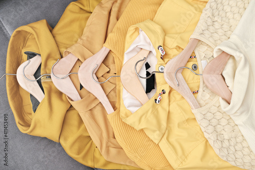 front view of Feminine clothes in yellow color on hanger. Spring cleaning home wardrobe. Minimal fashion concept. trendy color of the year 2021. total yellow look trend. monochrome outfit.