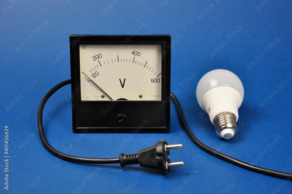Energy-saving light bulb and analog voltmeter. The concept of energy saving. Energy-saving light bulb and analog voltmeter. The concept of energy saving.