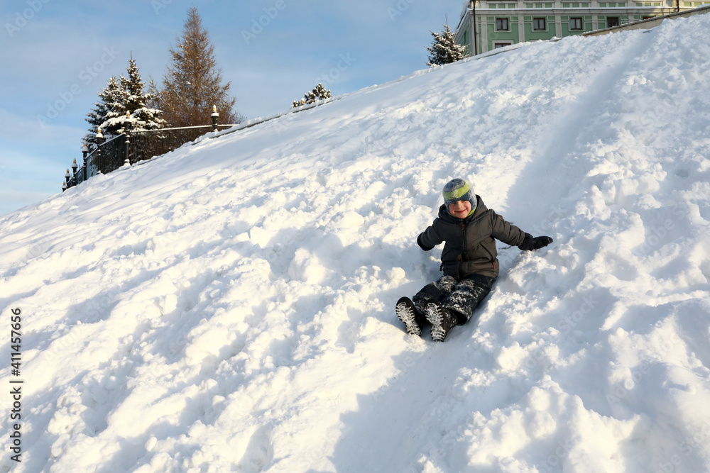 Boy rolling down snowy hill in Kazan Kremlin