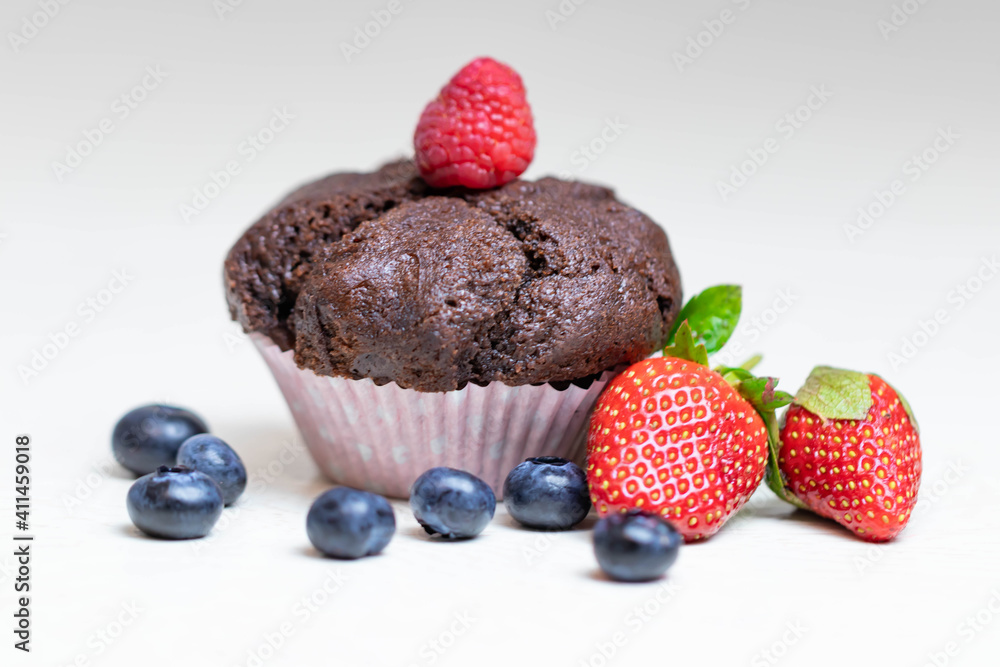 Baked chocolate muffin with juicy berries, strawberries, blueberries, raspberries. Baked chocolate muffin with juicy berries, strawberries, blueberries, raspberries.