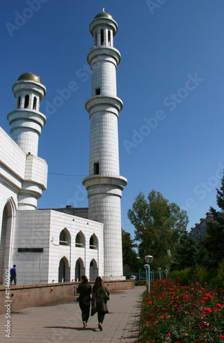Almaty, Kazakhstan - May 2018: The modern mosque with golden domes in front of mountains in good weather in the green city.