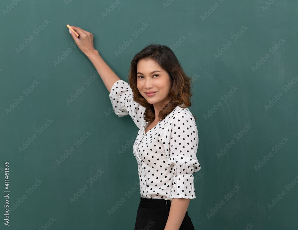 Beautiful Asian woman holding chalk standing in front of black board with copy space Beautiful Asian woman holding chalk standing in front of black board with copy space