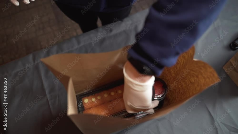Sushi packaging for delivery, a woman puts a set of sushi and sauce in a craft bag Sushi packaging for delivery, a woman puts a set of sushi and sauce in a craft bag