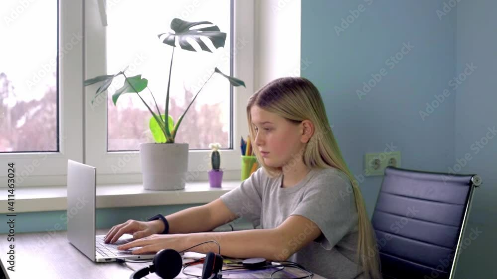 Teenage girl typing something on her laptop while having online lesson at home Teenage girl typing something on her laptop while having online lesson at home