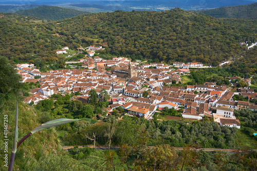 Pueblo de Alajar desde lo alto de una montaña, aparecen sus casas blancas con los tejado marrones y rodeado de un bosque verde. photo