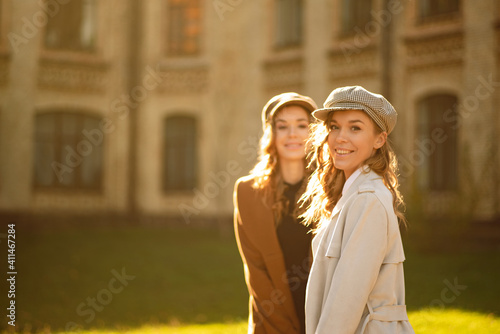 Two girls walking in city park and smilling
