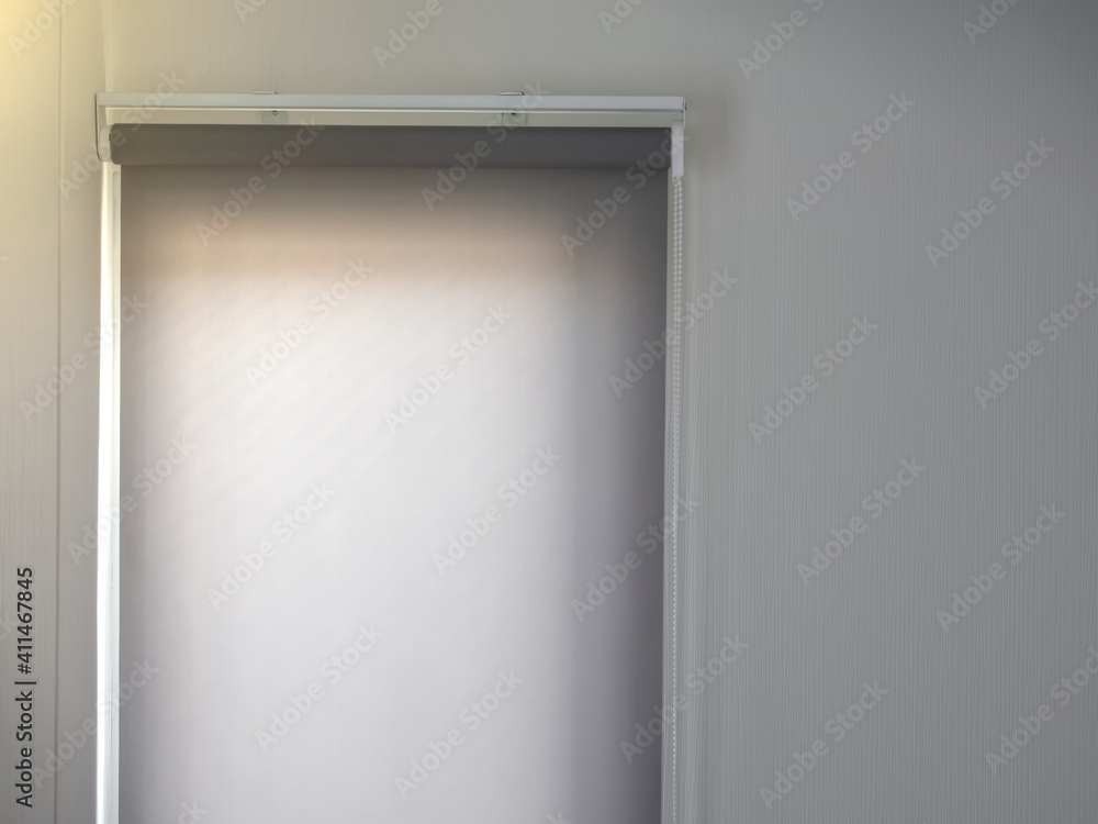 Roller blinds gray color on window, Protecting sunlight in summer season and white wallpaper in living room, Decoration minimal style with copy space. Roller blinds gray color on window, Protecting sunlight in summer season and white wallpaper in living room, Decoration minimal style with copy space.
