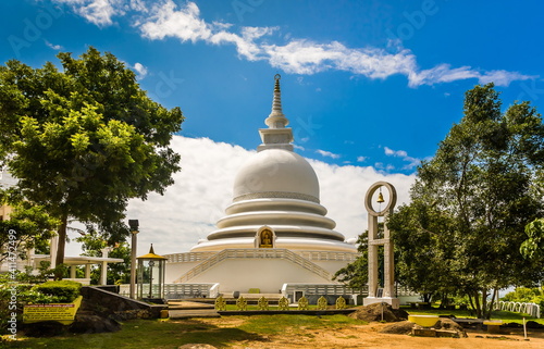A religious building in Sri Lanka against the background of leafy trees and a blue sky with white clouds