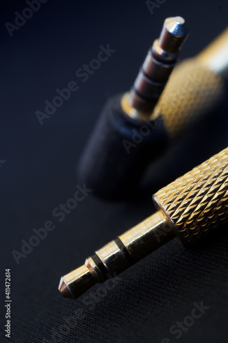 The gold-plated TRS connectors for analog audio are set against a black background. Mini-jack - 3.5 mm. Shallow depth of field