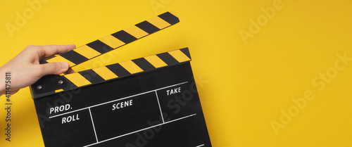 hand is holding yellow clapper board or movie slate or clapperboard.it use in video production ,film, movie,cinema industry on yellow background. photo