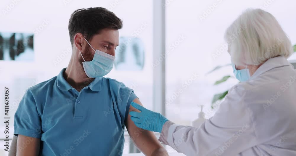 Young caucasian man participating in vaccination in medical laboratory. Doctor injecting experimental coronavirus vaccine for male customer patient. Young caucasian man participating in vaccination in medical laboratory. Doctor injecting experimental coronavirus vaccine for male customer patient.