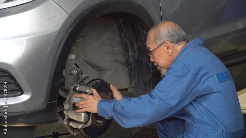 asian mechanic senior man car brake repairing in workshop at auto car repair service center. car engineer old man inspection vehicle details asian mechanic senior man car brake repairing in workshop at auto car repair service center. car engineer old man inspection vehicle details