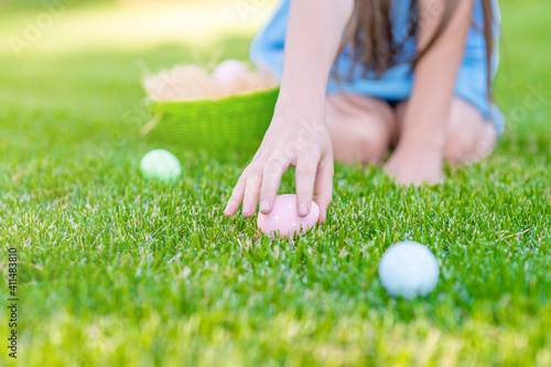Girl hunts for Easter eggs on summer grass