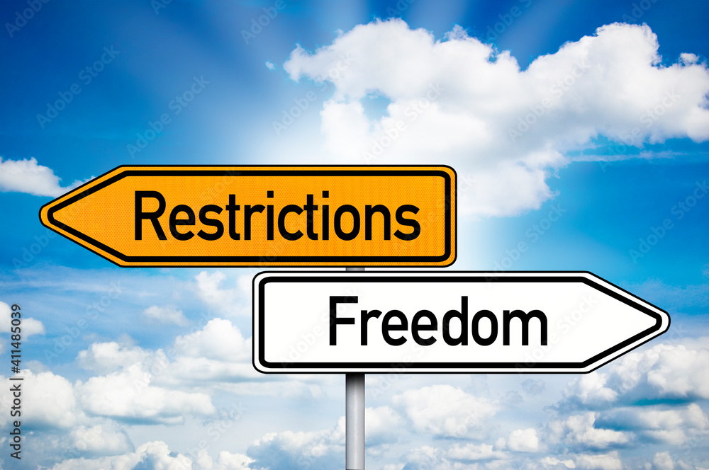 Road sign with words Restrictions and freedon in front of a blue sky Road sign with words Restrictions and freedon in front of a blue sky