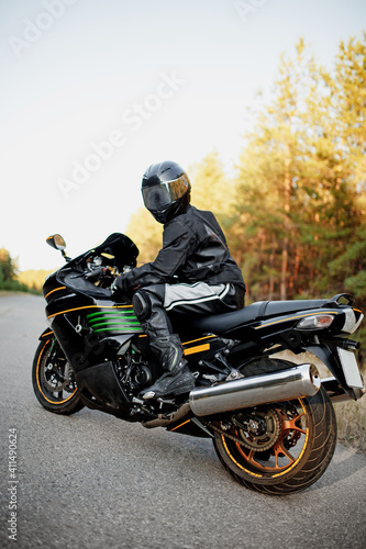 Motorcyclist in a helmet on a motorcycle on a country road. Guy driving a bike during a trip. Riding a modern sports motorcycle on the highway