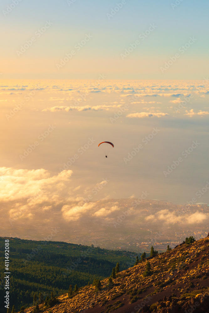 Paragliding over the clouds in the evening between green and yellow mountains at Teide National Park Paragliding over the clouds in the evening between green and yellow mountains at Teide National Park