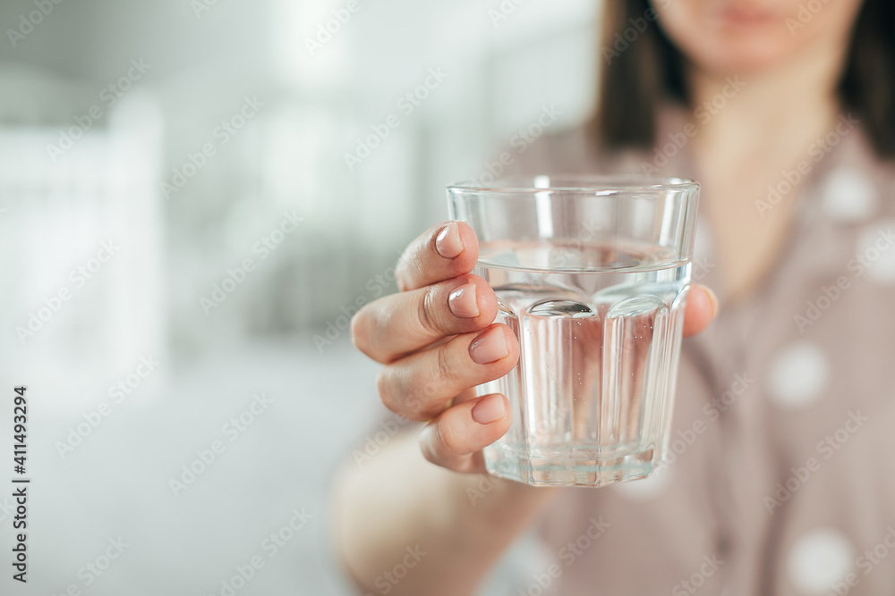 Young woman holding glass with water in hands. Self care concept. Formation of healthy useful habit Young woman holding glass with water in hands. Self care concept. Formation of healthy useful habit