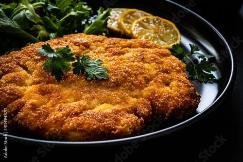 Fotografie Breaded fried pork chop and fresh vegetables on black table