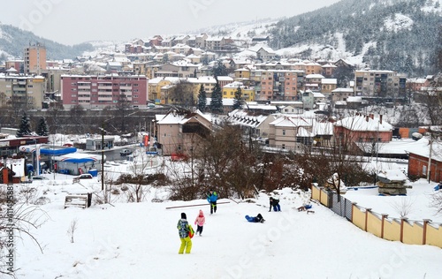 the children are sledding on the hill, and the city can be seen in the background