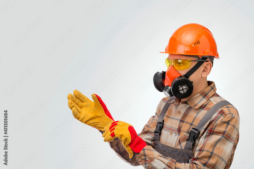 Fototapeta premium Construction worker putting on protective gloves over gray background. Personal safety equipment.
