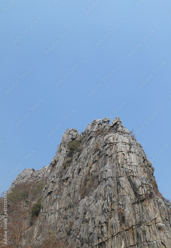 Closeup of the top of rocky mountain with blue sky background. Vertical view. Closeup of the top of rocky mountain with blue sky background. Vertical view.