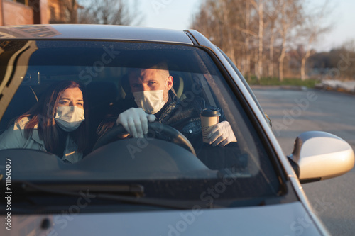 A man and a woman wearing medical masks and rubber gloves to protect themselves from bacteria and viruses while driving a car. masked men in the car. coronavirus, covid-19.