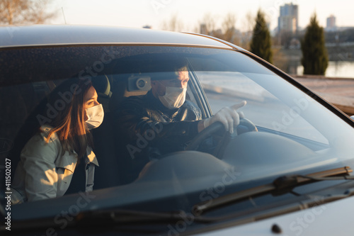 A man and a woman wearing medical masks and rubber gloves to protect themselves from bacteria and viruses while driving a car. masked men in the car. coronavirus, covid-19. © Artem Zakharov