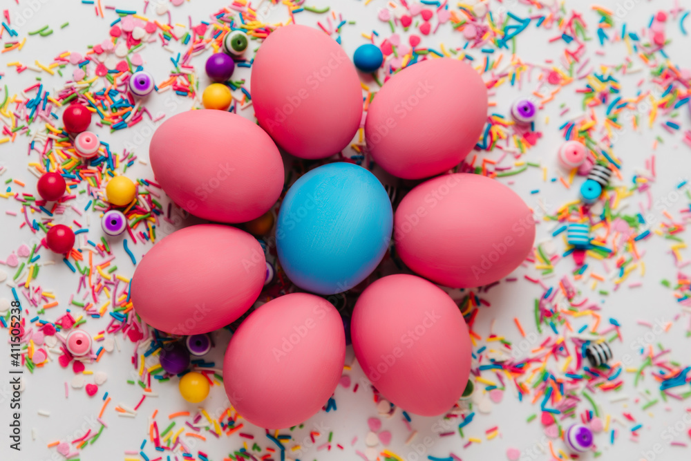 colorful eggs laid with a flower on a background of colored beads and powder colorful eggs laid with a flower on a background of colored beads and powder