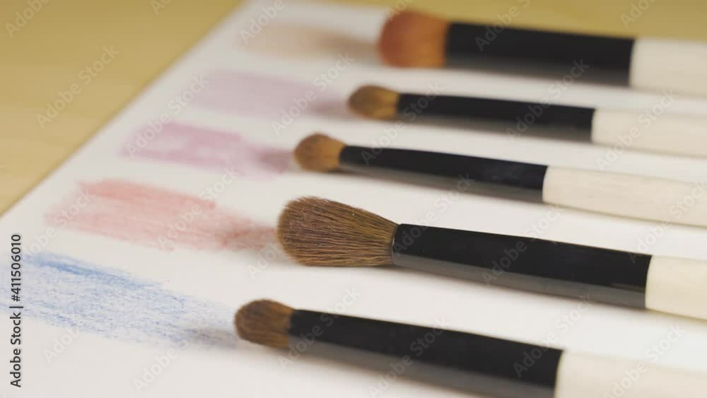 makeup brushes in a row on a paper with color swatches. Panning movement makeup brushes in a row on a paper with color swatches. Panning movement