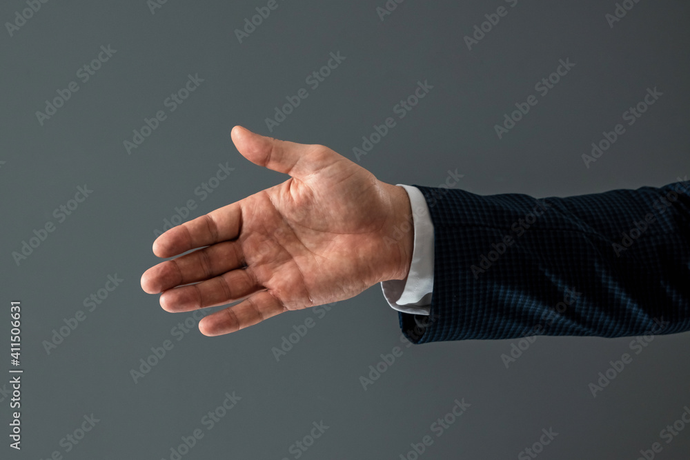 Male hand in suit shows thumbs up gesture on gray background. Concept ok, approval, close-up. Male hand in suit shows thumbs up gesture on gray background. Concept ok, approval, close-up.