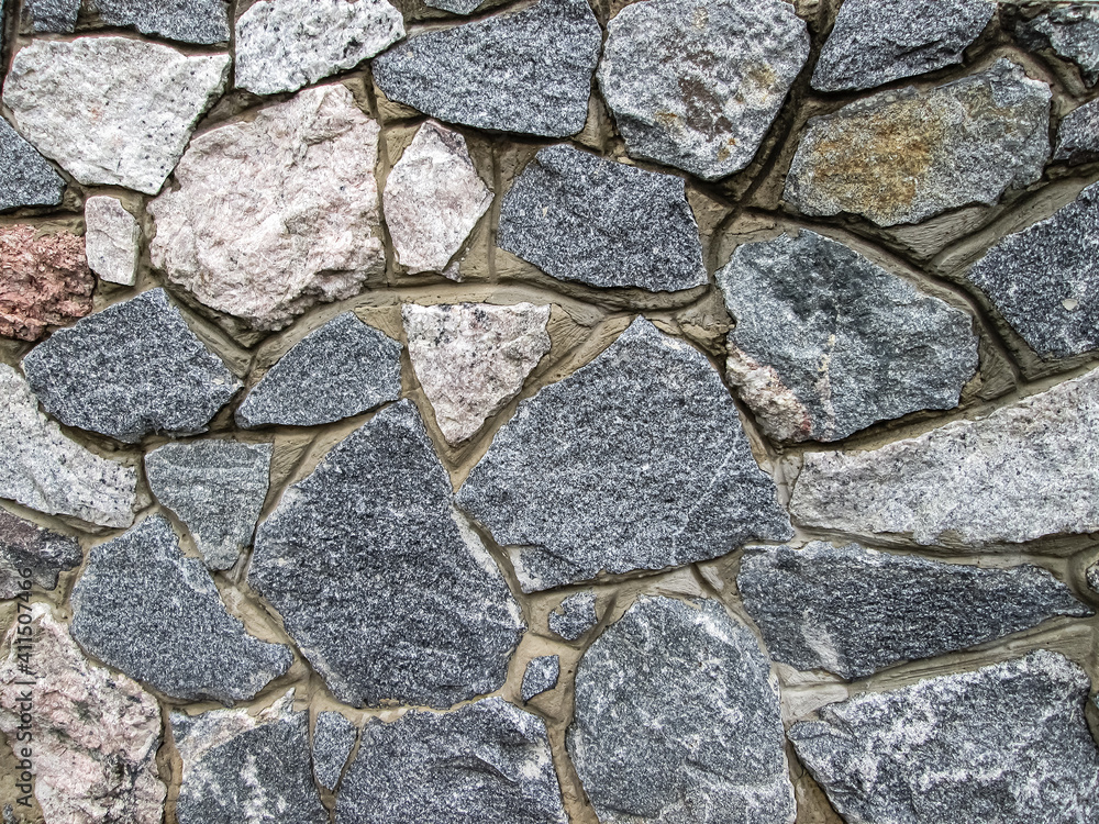 Smooth gray stones embedded in the wall. Cobblestone cover. Smooth gray stones embedded in the wall. Cobblestone cover.