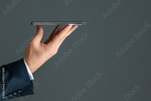 A businessman in a business suit holds a smartphone in his hands. Online business concept, networking, freelance.