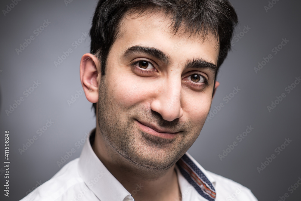 Fototapeta premium Portrait of caucasian man with brown eyes expressing positive emotions in studio, with grey background