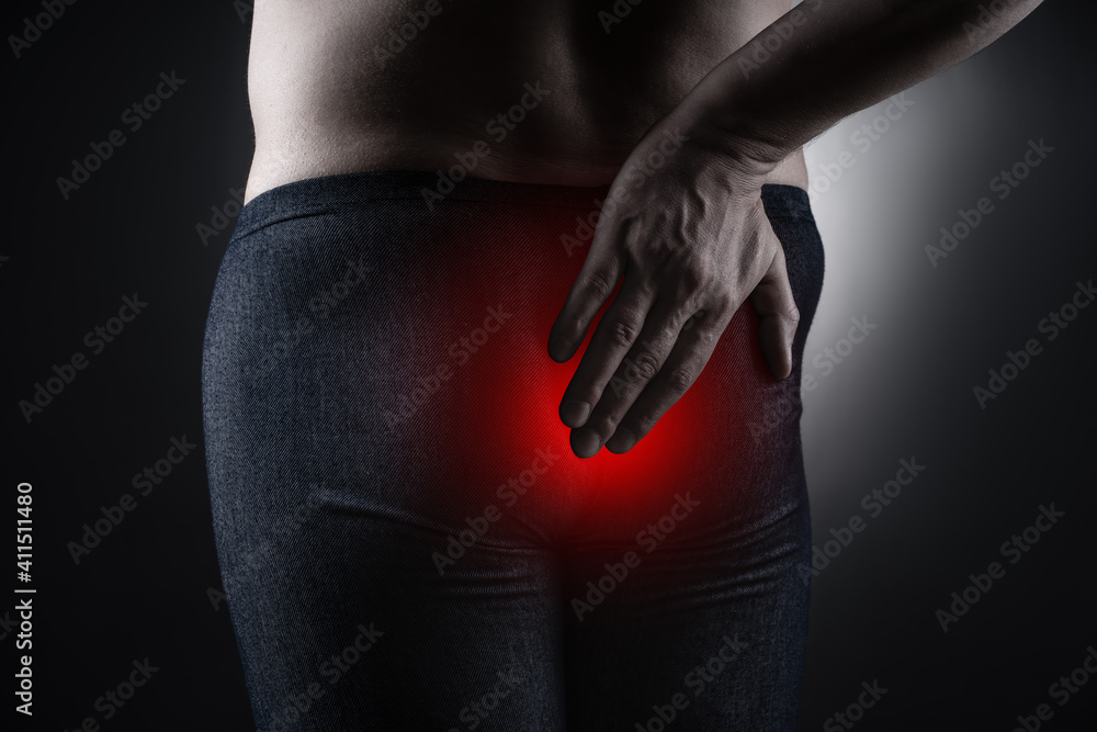 Fototapeta premium Man suffering from hemorrhoids, anal pain on black background
