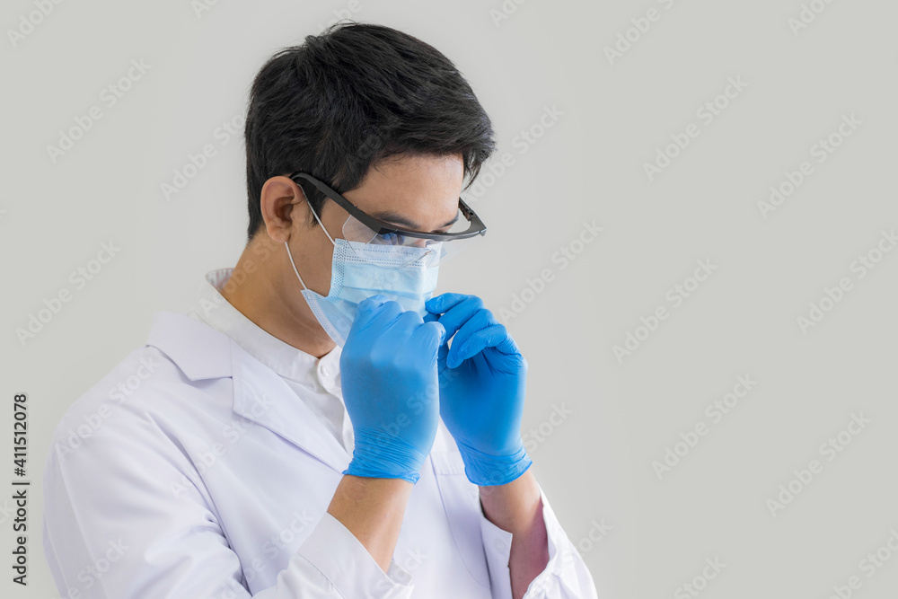 Close up male doctor, researcher, scientist wearing eye protection glasses, white suit, glove and mask on grey background. Healthcare and medical concept. Close up male doctor, researcher, scientist wearing eye protection glasses, white suit, glove and mask on grey background. Healthcare and medical concept.