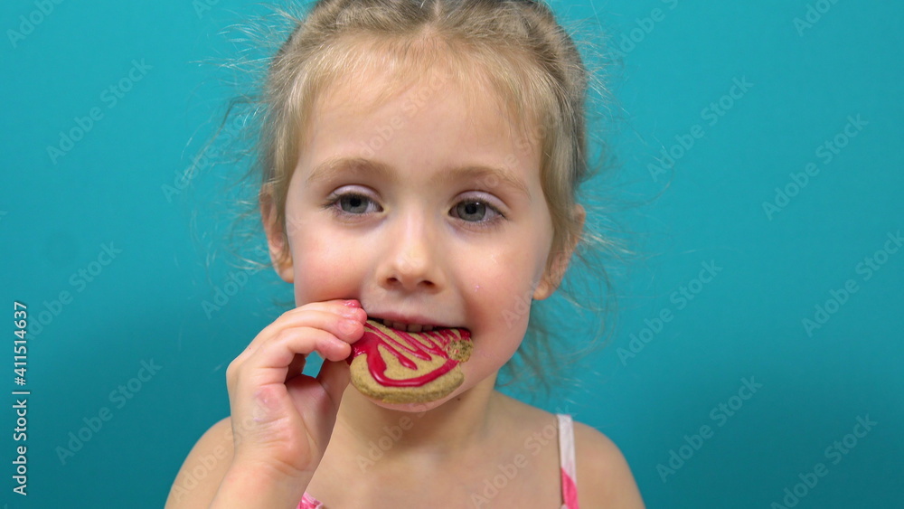 The girl tries a heart-shaped cookie she made herself. Making cookies for Valentine's Day The girl tries a heart-shaped cookie she made herself. Making cookies for Valentine's Day