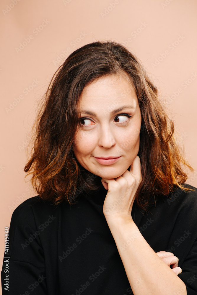 Obraz premium Sceptical smile on a face of tired middle aged woman. She's looking the side, hand of her neck. She has subtle cat eye makeup, she wears black shirt