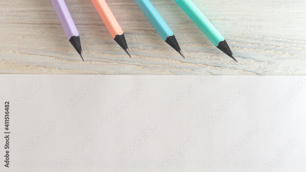 Pencils in delicate pastel colors, pink, mint, blue, lilac on a white wooden background. Space for text white sheet of paper Pencils in delicate pastel colors, pink, mint, blue, lilac on a white wooden background. Space for text white sheet of paper