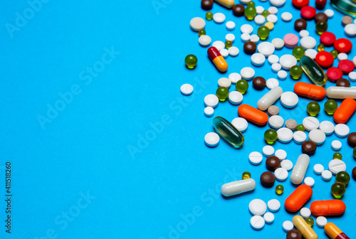 Antiviral capsules, tablets for treatment lie on a blue background. multi-colored capsules. wad health care concept from top